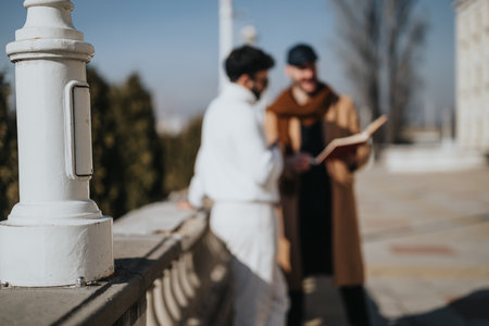 Casual business meeting between two fashionably dressed men, with one holding a notebook, discussing...