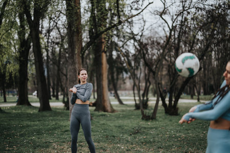Active sports girl playing soccer with a friend outdoors in the parkの写真素材