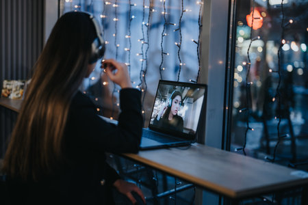 Young female person engaged in a video conference at evening.の写真素材