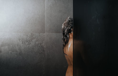 Woman showering, personal hygiene routine captured in a modern bathroom settingの写真素材