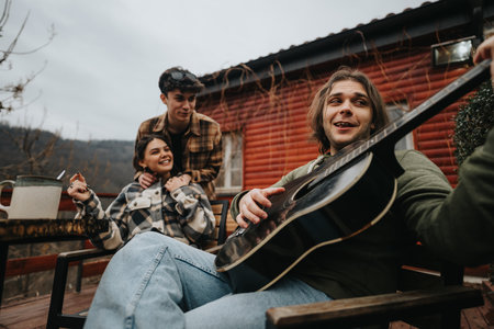 Friends enjoying a casual guitar session outdoors on a wooden deck.