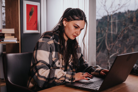 Young woman using laptop at home in a casual settingの写真素材