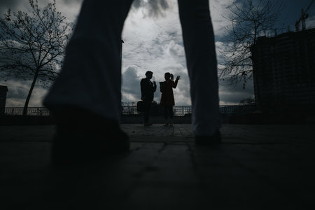 Silhouette of a couple in a dramatic urban setting with moody skyの写真素材