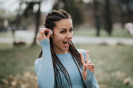 Active sports girl enjoying a break in the park with a peace signの写真素材
