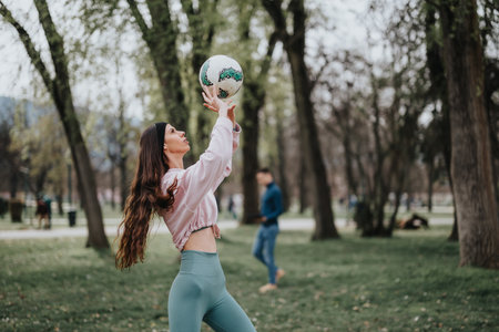 Active sports girl playing with a soccer ball outdoors in a parkの写真素材