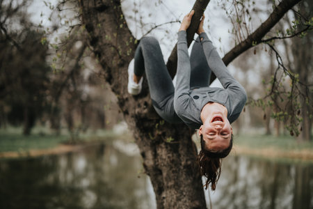 Active sports girl enjoying a workout outdoors hanging from a tree