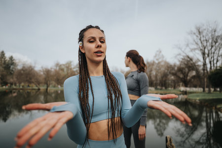 Young woman practicing yoga in a peaceful park setting with friendの写真素材