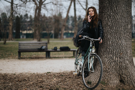 Stylish businesswoman on a break outdoors with bicycle and phoneの写真素材