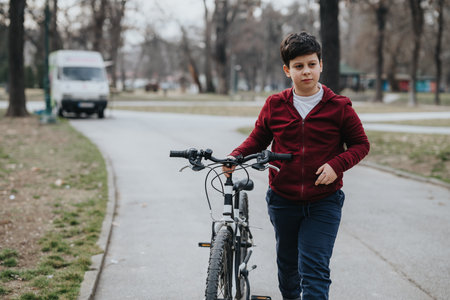 Young boy walking with his bicycle in a park, enjoying a day outdoorsの写真素材