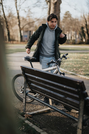 Man taking a break on a bench with his bicycle in a sunny park