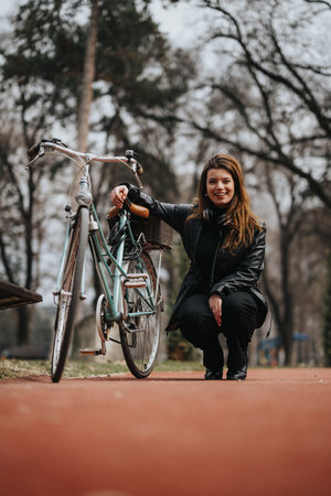 Smiling businesswoman with bicycle taking a break in an urban parkの写真素材