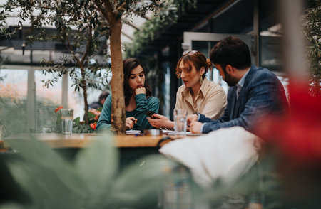 Entrepreneurial team engaged in a lively business meeting at a cozy urban coffee shopの写真素材