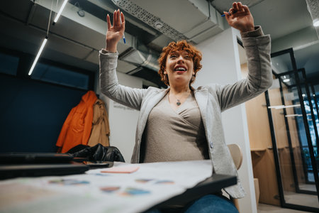 Female employee working on market expansion and analyzing statistics for business development and profit growth. She is celebrating success.の写真素材