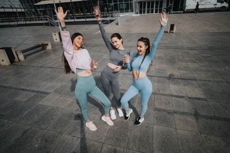 Three joyful women in sportswear celebrating outdoors