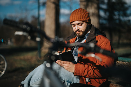 Casual man using smart phone with bike in a park on a sunny dayの写真素材