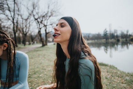 Joyful young women resting after a run in a scenic park, friendship and fitnessの写真素材