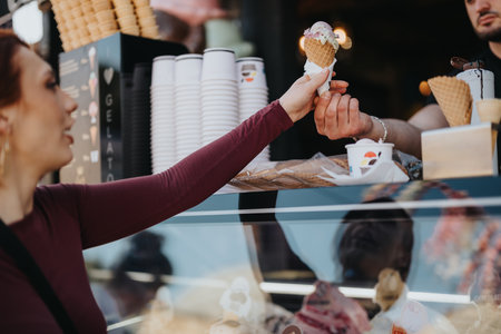 Young woman receiving a scoop of ice cream from a vendor on a sunny day