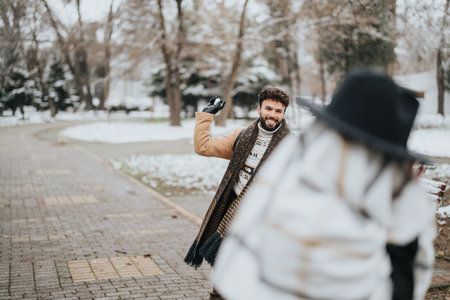 In the frame, a young man in business casual attire smiles during a snowy day, engaging with a colleague outside.の写真素材