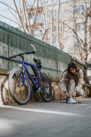 Active woman tying shoelaces before cycling in an urban environment.