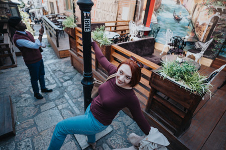 Joyful woman stretching on a city street with a man in the backgroundの写真素材