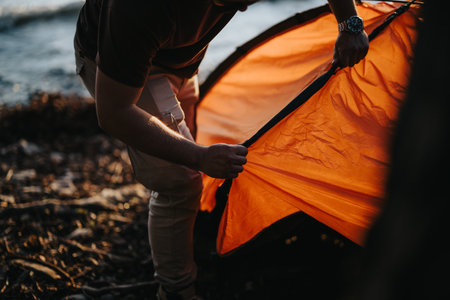 Friends setting up a tent by the lake during a weekend camping tripの写真素材