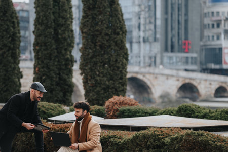 Two men engaged in a casual business meeting outdoors in the city.の写真素材