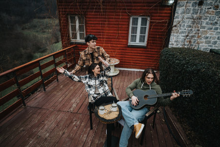 Friends enjoying a relaxed guitar session on cabin porch.の写真素材