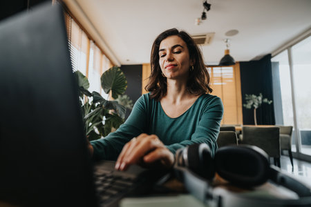 Confident female entrepreneur working on laptop in modern officeの写真素材