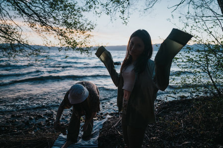Friends enjoying an adventure outdoors near a lake at duskの写真素材