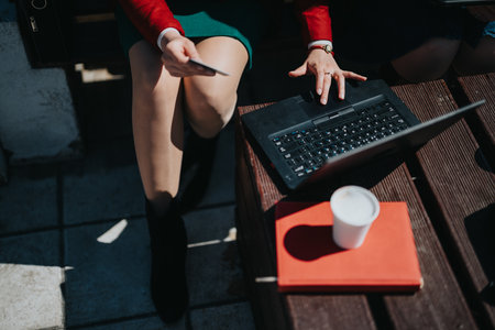 Businesswoman with laptop conducting outdoor meeting in sunlightの写真素材