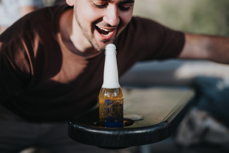 Man laughing and leaning towards an unopened beer bottle on a tableの写真素材