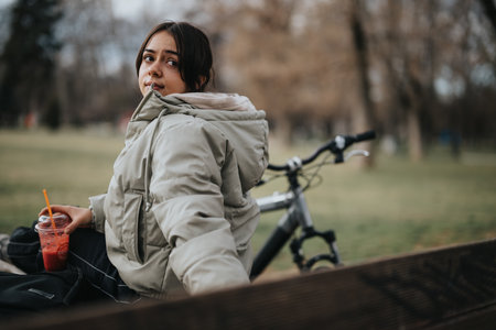 Casual young girl enjoying a peaceful break with her bicycle in the park