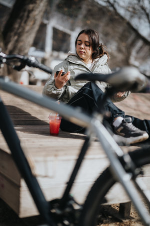 Young woman enjoying a peaceful moment with her bicycle in a sunny parkの写真素材