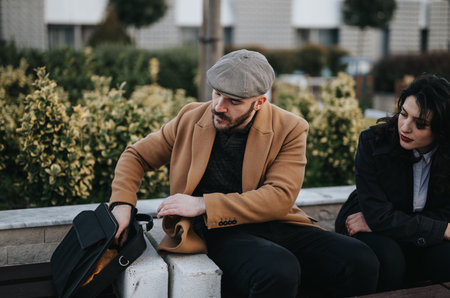 Contemplative couple sitting outdoors with man checking on bag.