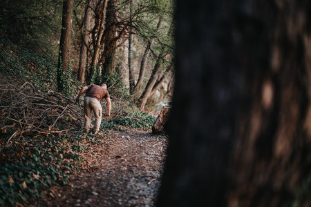 Man in brown shirt diligently clearing a forest path, engaging in environmental conservation workの写真素材