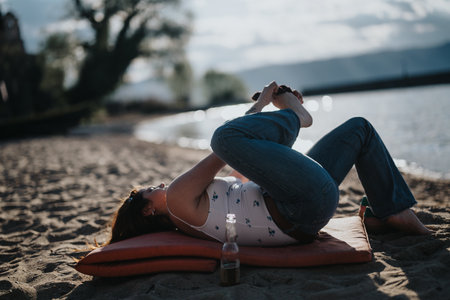 Young woman stretching on a sunny beach during a relaxing vacation by the lakeの写真素材