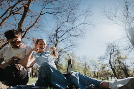 High school students collaborating on homework in a sunny outdoor campus settingの写真素材