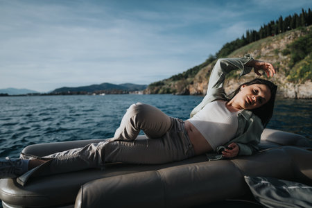 Carefree young adult relaxing on a boat in the lake on a sunny dayの写真素材