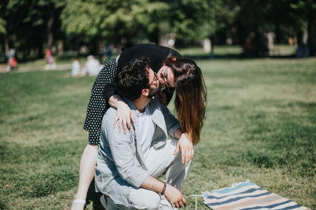 Affectionate young couple enjoying a sunny day in the park, embracing and kissingの写真素材