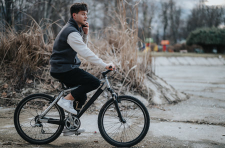 Young male teenager riding a bicycle on park pathway during autumnの写真素材