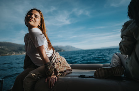 Happy girl enjoying a serene boat ride on a sunny dayの写真素材