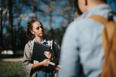 School friends discussing academic topics in a sunny urban park after examsの写真素材