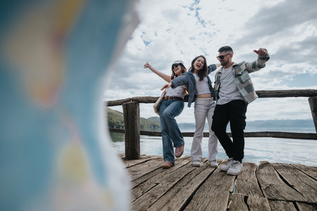 Friends enjoying a scenic lakeside journey, posing with joy on a wooden pier during their tripの写真素材