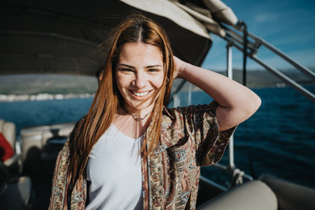 Smiling young woman enjoying a boat trip with friends on a sunny weekendの写真素材