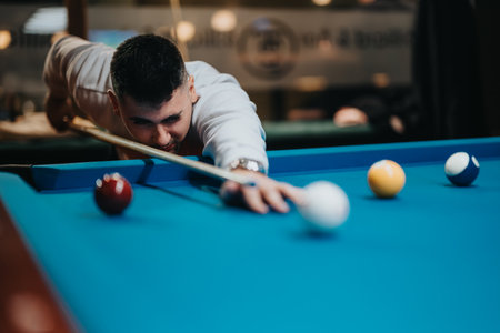 Focused man lining up shot in a casual game of billiards with friends