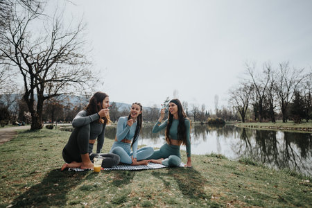 Active friends enjoying a peaceful yoga session outdoors by the lakeの写真素材