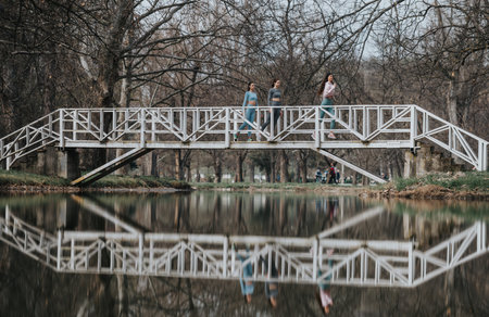 Friends enjoying a leisurely walk on a park bridge over a serene lake
