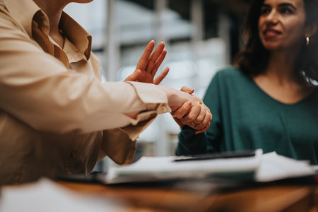 Business professionals engaging in a firm handshake over a meeting tableの写真素材