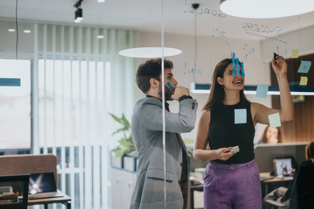 Business team brainstorming ideas with sticky notes on a glass wall in modern officeの写真素材