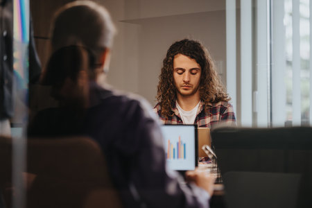Young entrepreneurs in a meeting room discussing growth and investments, using graphs on a tabletの写真素材